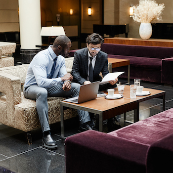 2 colleagues meeting in a hotel lobby discussing ways to improve the customer experience within the hospitality industry